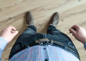 A point of view shot of a male office worker looking at their shirt, jean and brown laced shoes