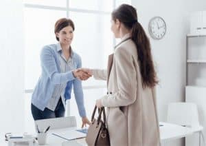 An interviewer welcomes an interviewee with a handshake