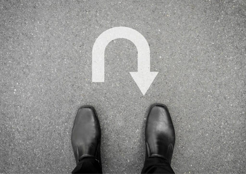 An aerial view of a worker standing in front of a white U turn sign painted on the road